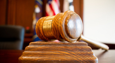 Close up image of the Herriman Justice Court gavel with flags in the background.