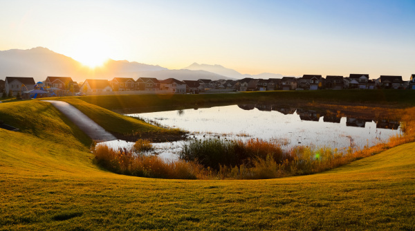 Detention pond in Herriman near Mountain Ridge High School with a neighborhood and sunrise in the background