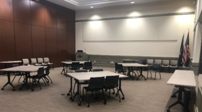 A picture of an enclosed half of the Herriman city hall community room with a series of tables and chairs.