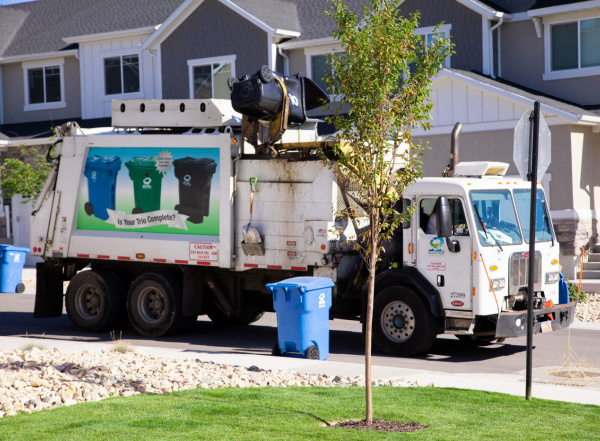 A Wasatch Front Waste truck empties a garbage can.