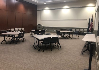 A picture of an enclosed half of the Herriman city hall community room with a series of tables and chairs.